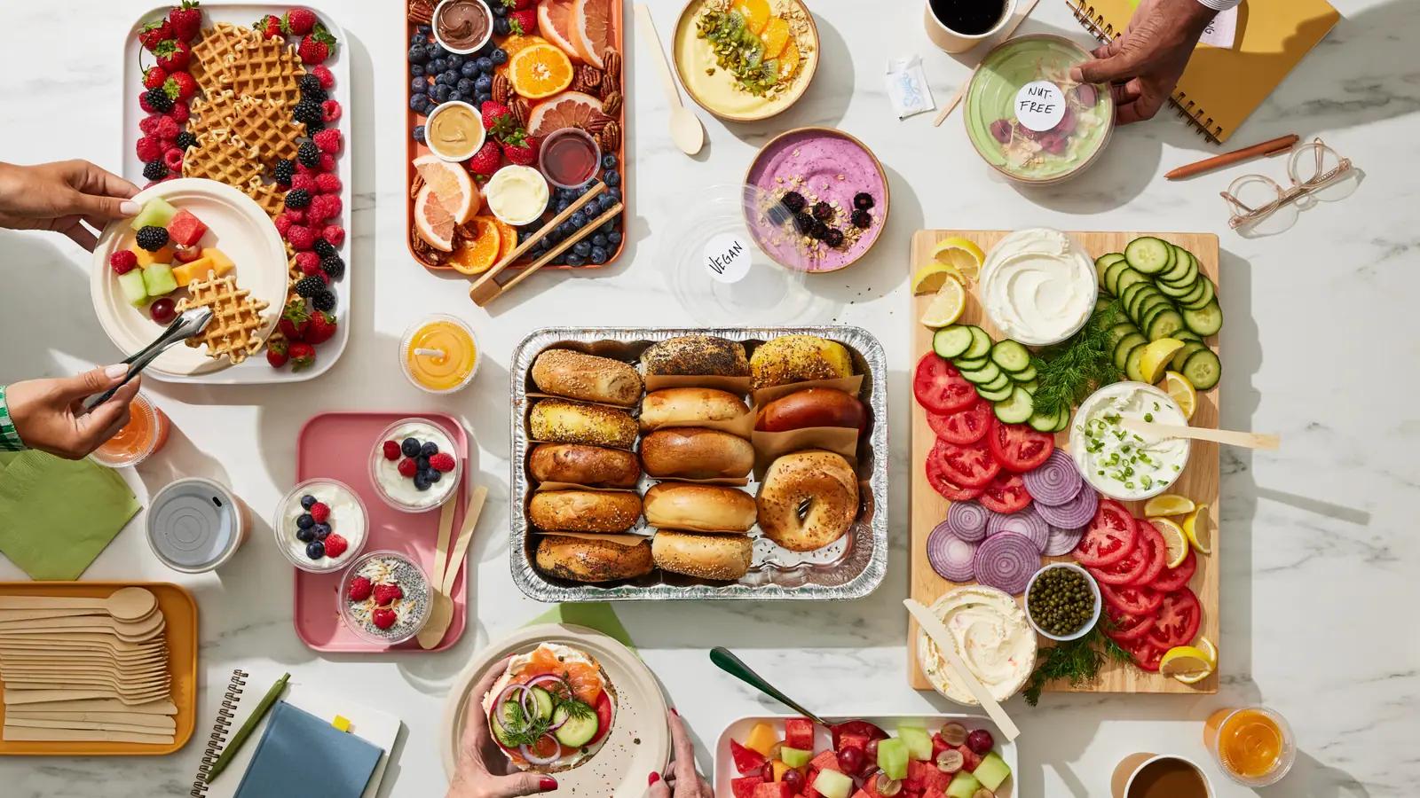 A breakfast spread with waffles, fruit, bagels and yoghurt pots