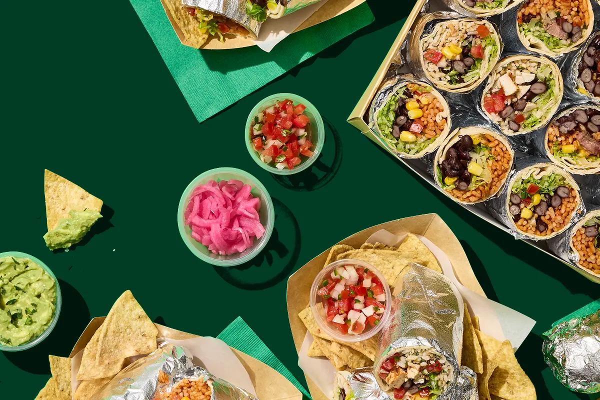Burritos, rice bowls, chips and salsa on a table