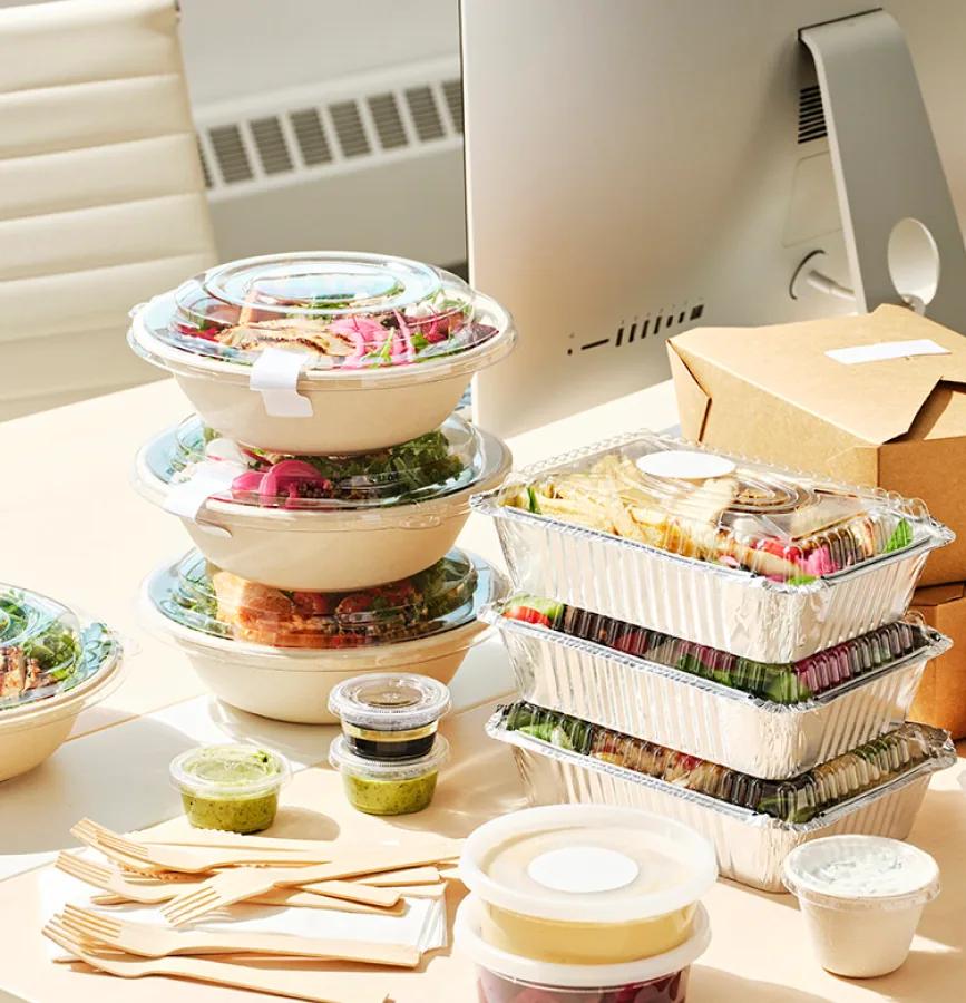 Individually packed lunch bowls and boxes on an office desk