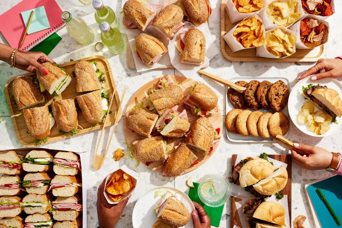 Platters of sandwiches, crisps and cookies on a table, seen from above